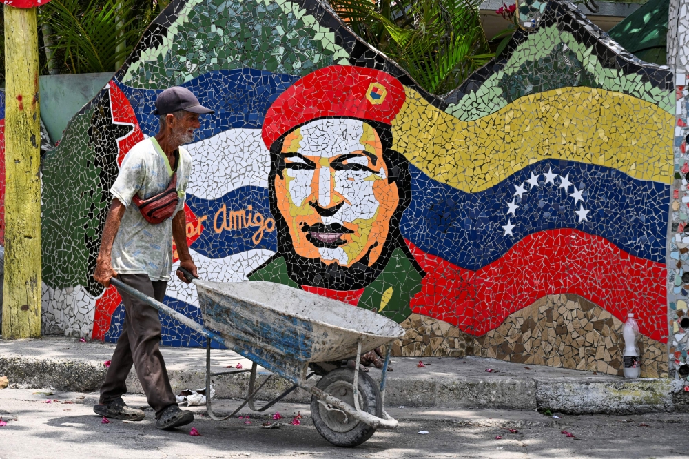 A man walks in front of artwork by Cuban artist Jose Fuster depicting late Cuba's leader Fidel Castro (L) and late Venezuela's President Hugo Chavez in the seaside village of Jaimanitas on the outskirts of Havana April 30, 2025. — AFP pic